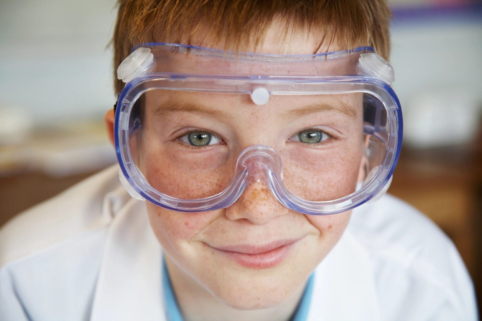 Young boy wearing oversized safety goggles and smiling.
